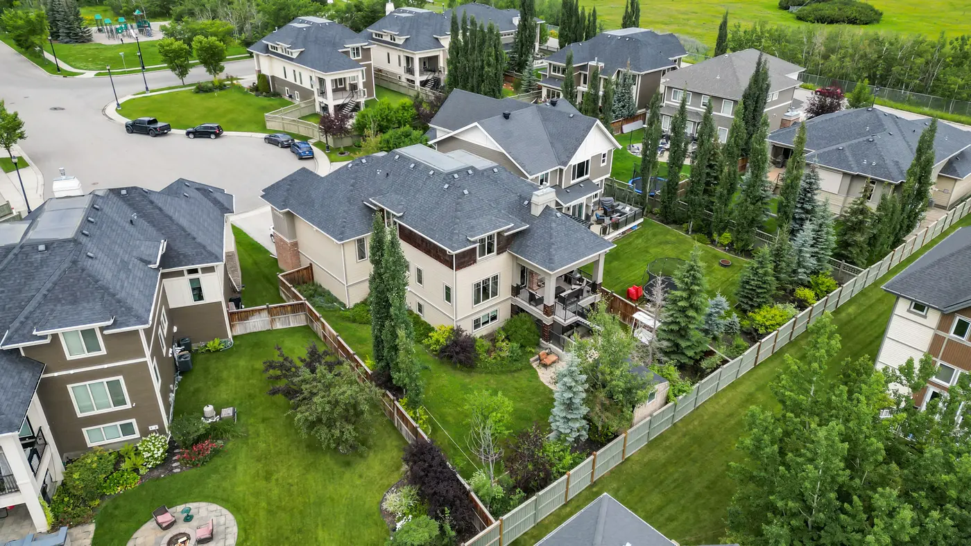 An aerial over the back corner of the pie-shaped lot, the landscaped yard and covered deck below and the Wentworth Square playground visible up the street.