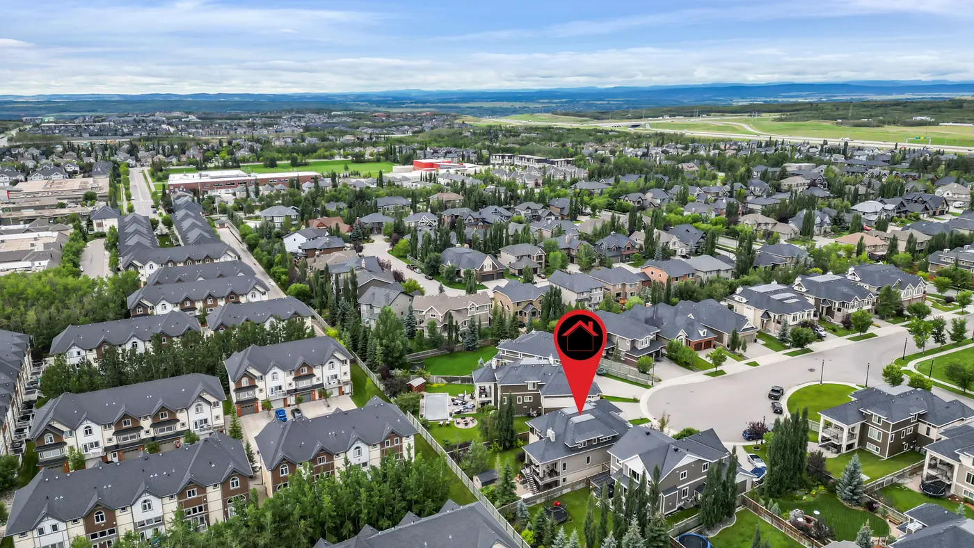 A high aerial marking the home within West Springs, tree-lined streets running toward the foothills on the western horizon.