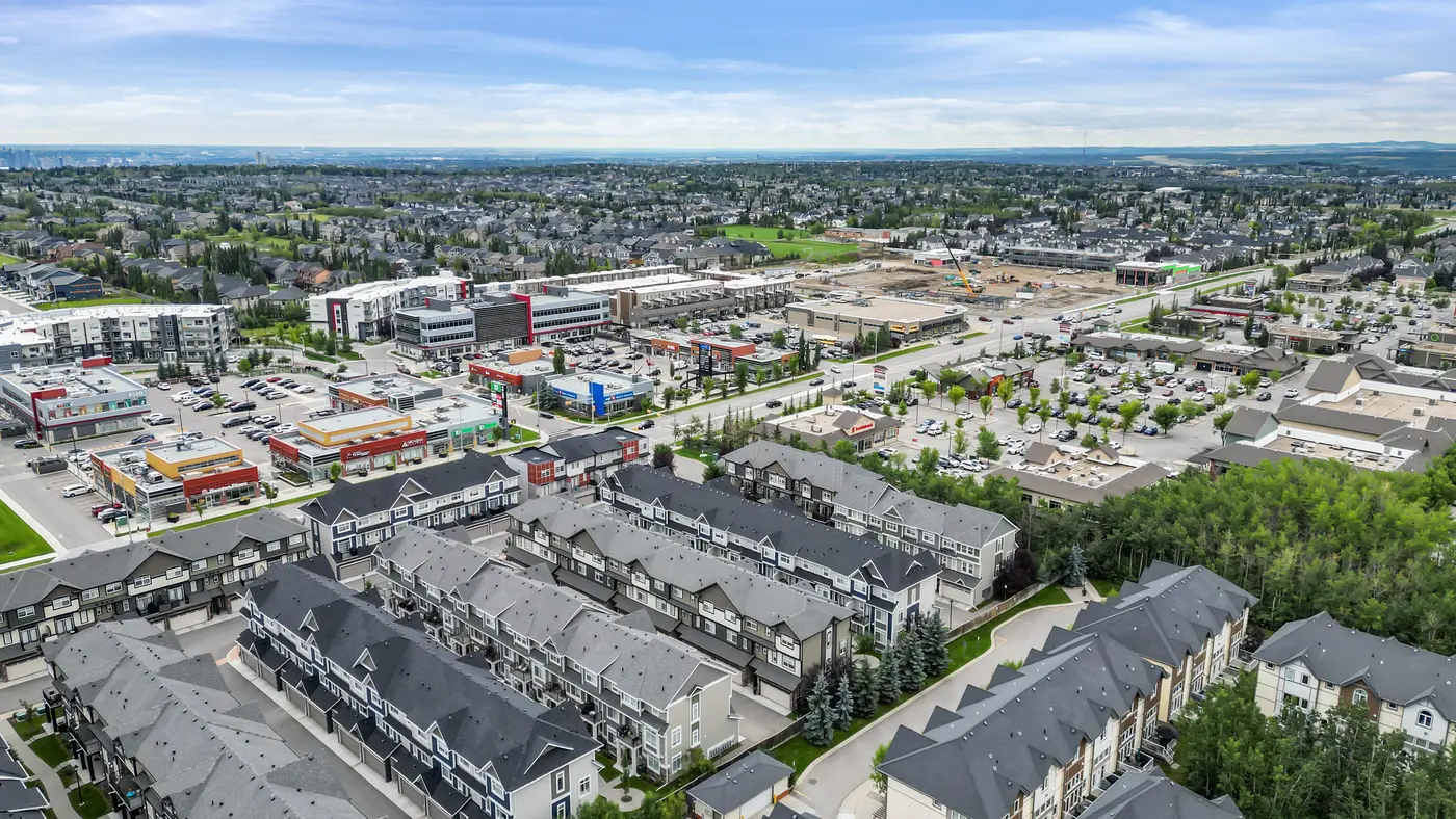 An aerial over the retail blocks at the edge of West Springs, the city opening up beyond.