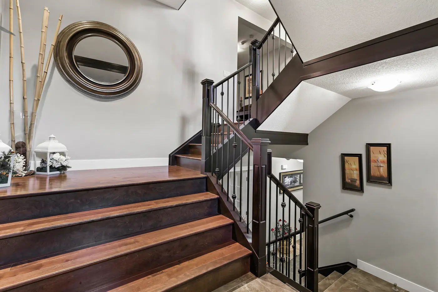 The central staircase in dark-stained maple with wrought-iron spindles, splitting toward the upper floor and the walkout level below.