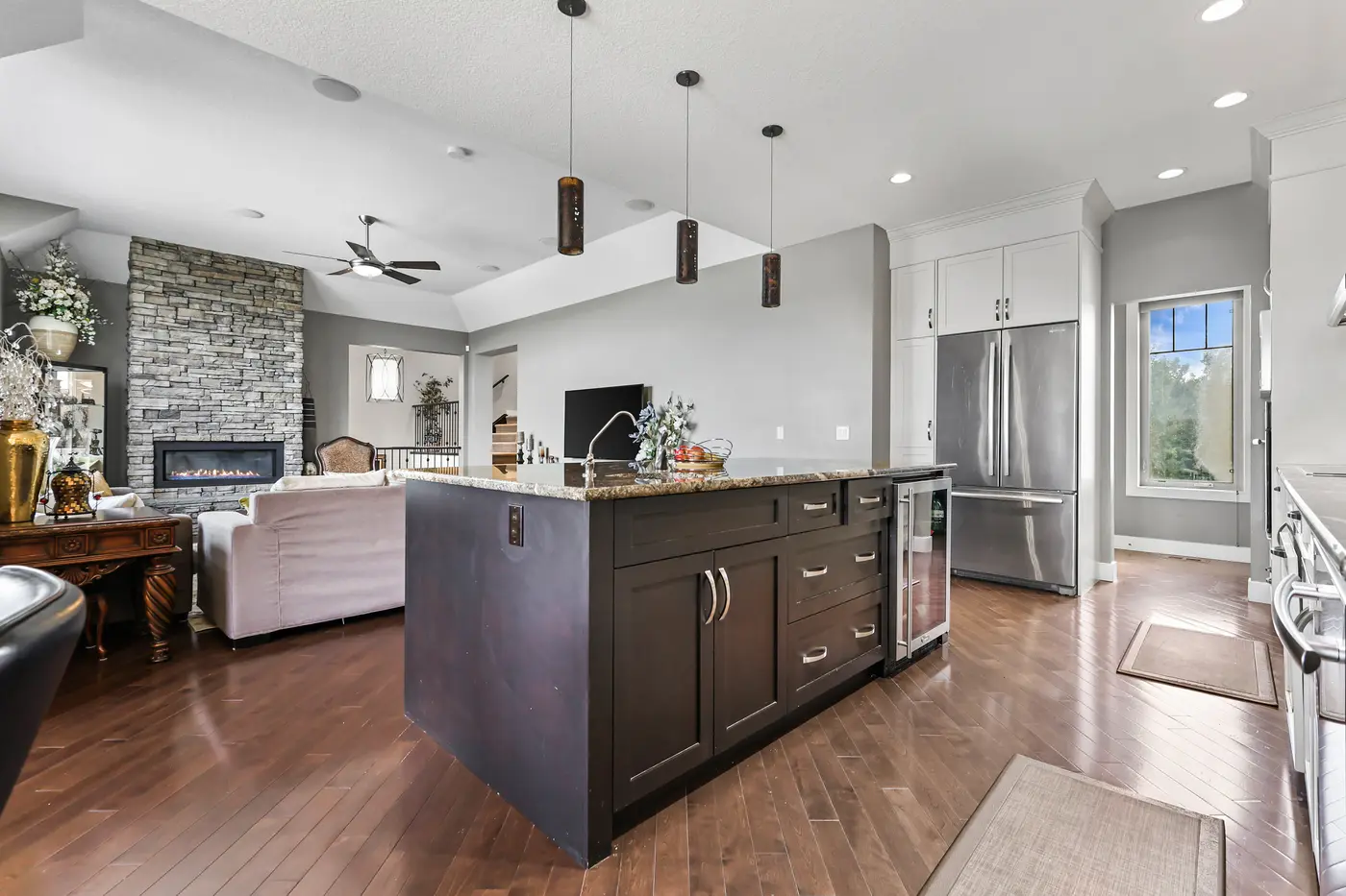 From the kitchen island across the great room to the stone fireplace, the whole main floor visible in one glance.