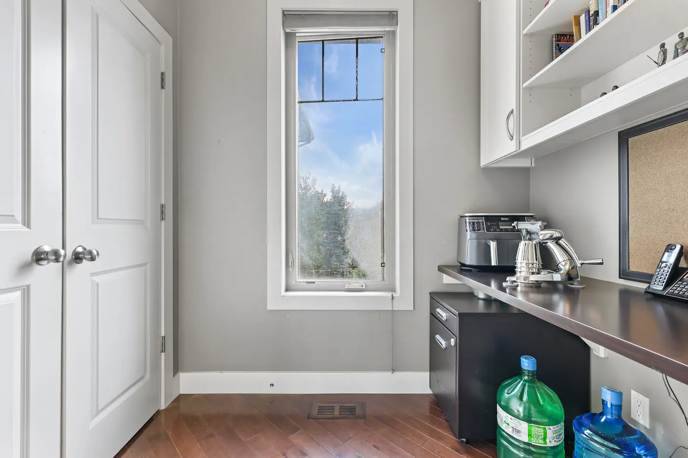 The walk-through pantry and coffee station off the kitchen, with a work counter, open shelving, and a bright window.