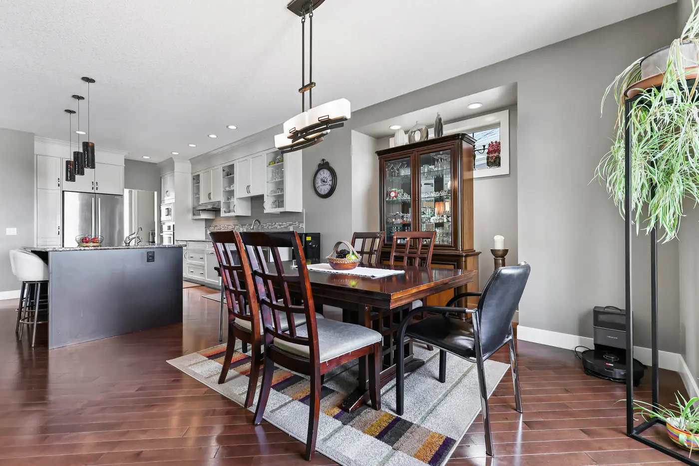 The dining area with its china cabinet, the kitchen island and pendants carrying on behind.