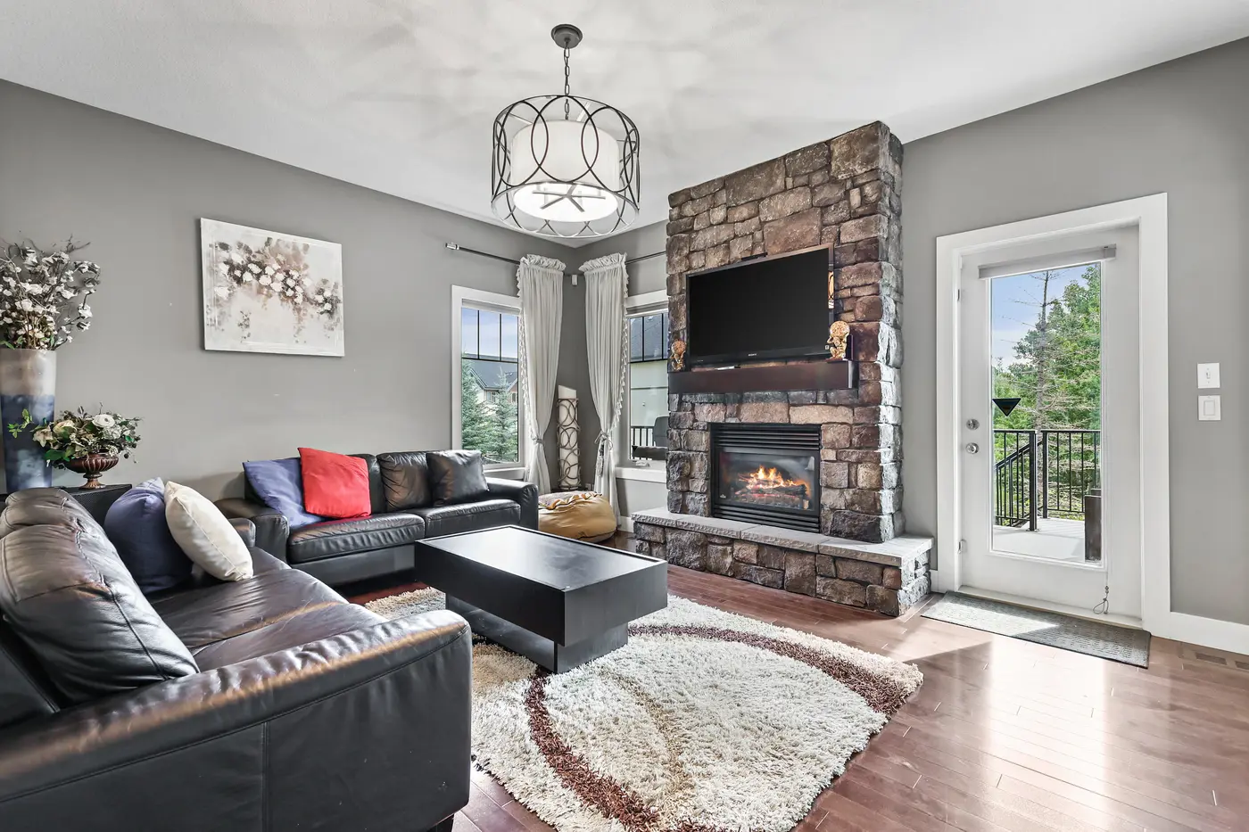 The retreat’s private living room — a stone-faced gas fireplace, leather seating, and a glass door leading out to the covered patio.