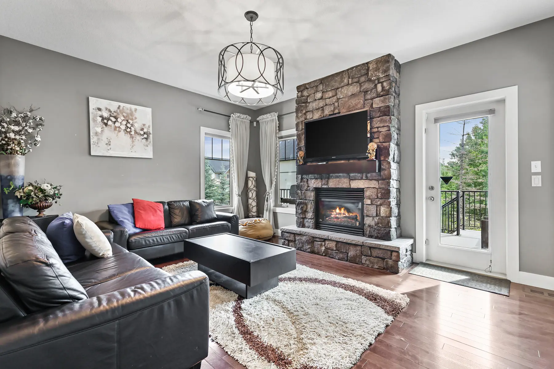 The retreat’s private living room — a stone-faced gas fireplace, leather seating, and a glass door leading out to the covered patio.