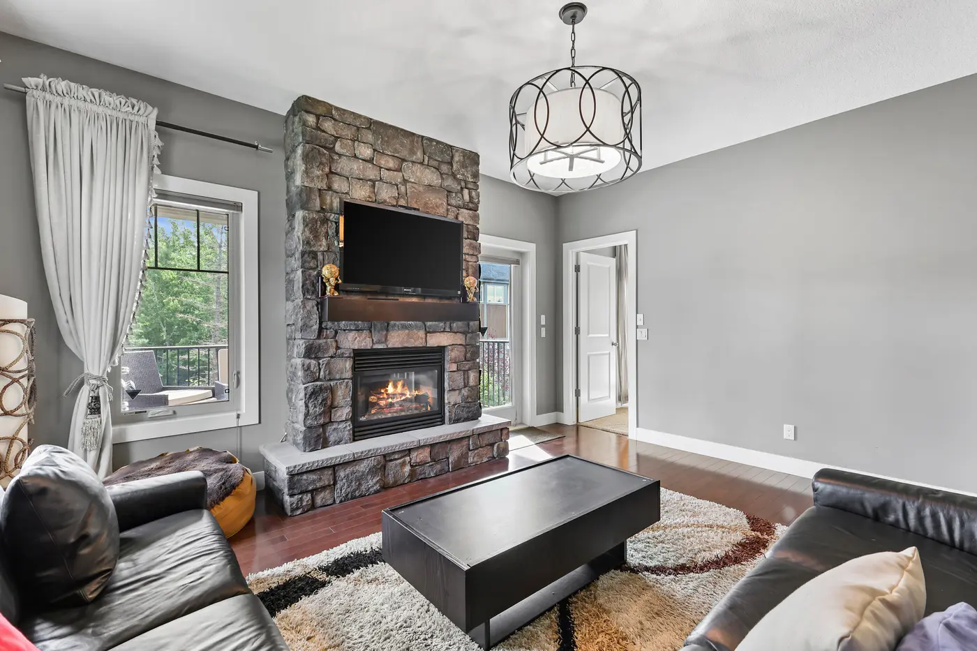 The private sitting room’s stone fireplace, lit, with the doorway back toward the primary bedroom at right.