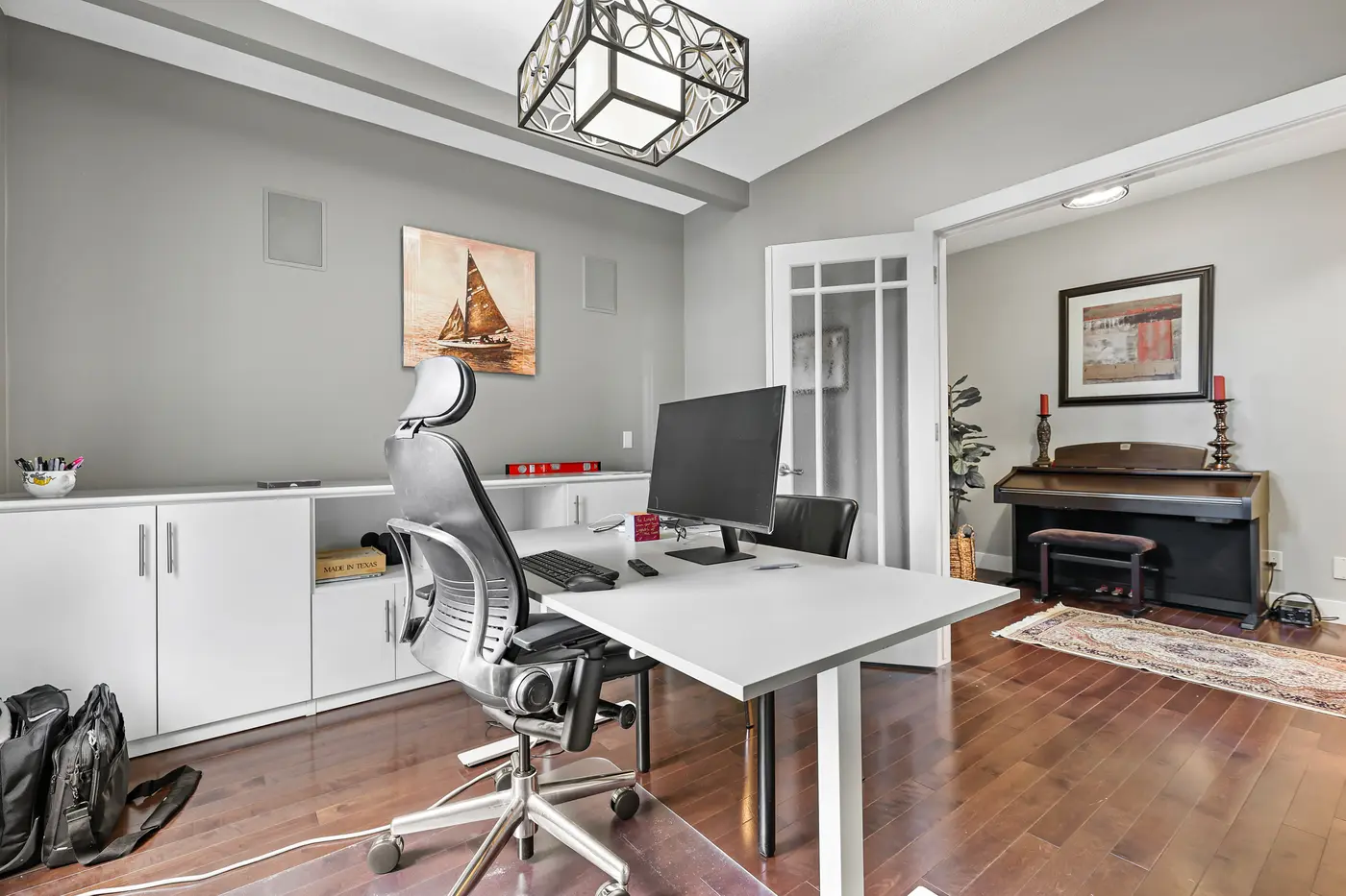 The den from the desk, its glass-panel French doors opening to the piano room and the front hall.