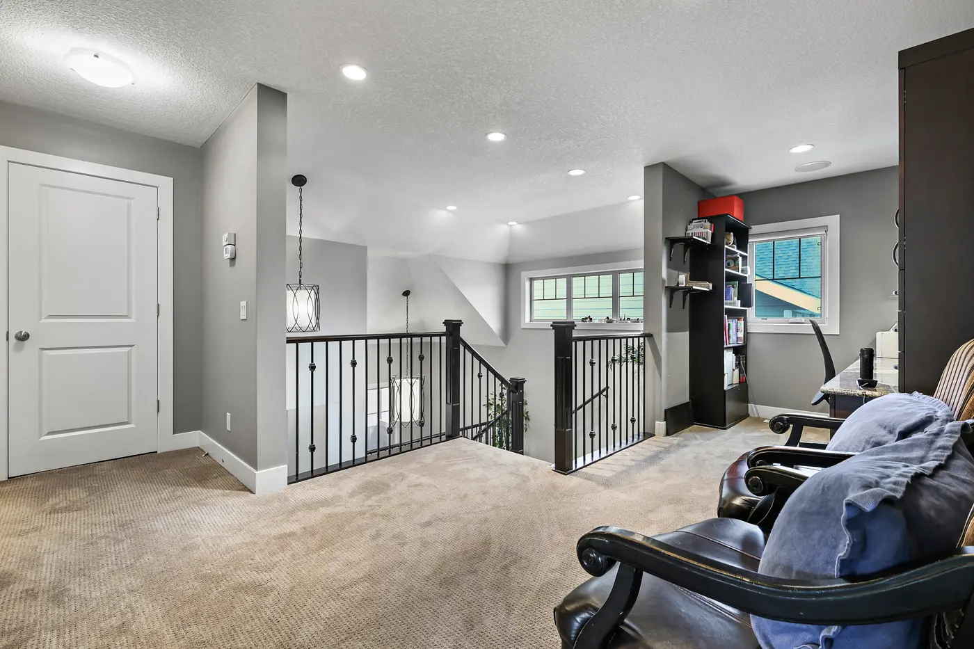 The upper landing and flex area, open over the stairwell on two sides, with a window bringing in the afternoon.