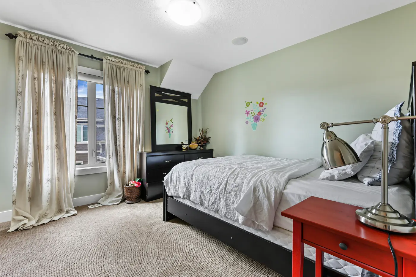 The third upstairs bedroom, soft light through double curtained windows, a mirrored dresser at the wall.