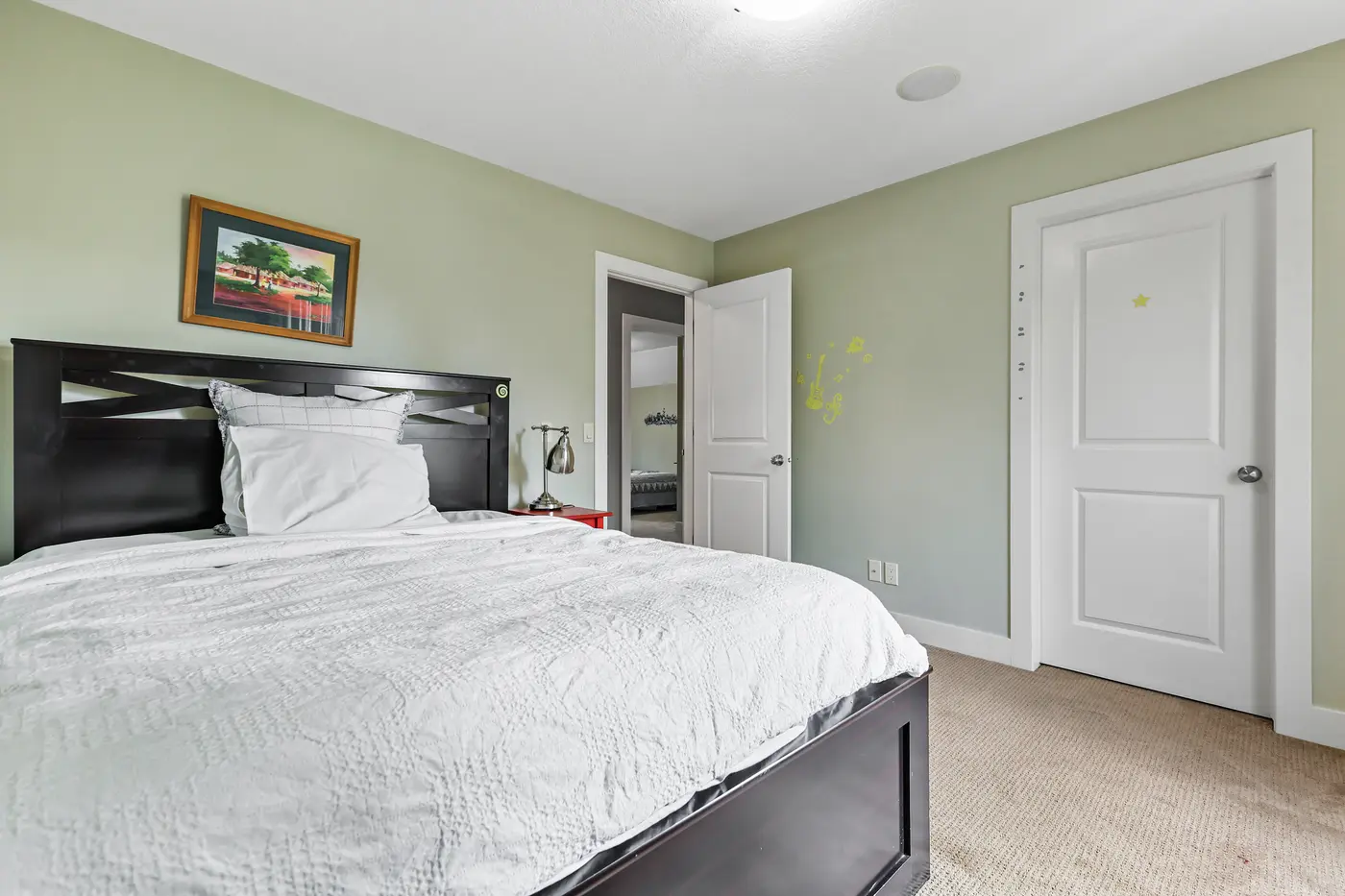 The third upstairs bedroom from the window, its dark wood bed facing the closet and hall door.