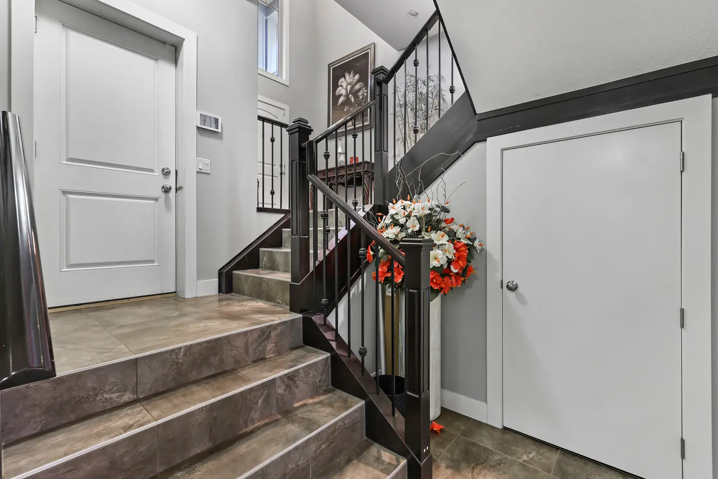 The lower foyer off the walkout level, tiled and bright, where the staircase turns up toward the main floor.