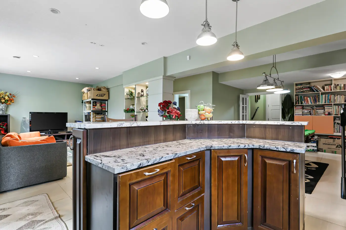 The curved granite bar counter of the walkout kitchenette, cabinetry in warm wood below.