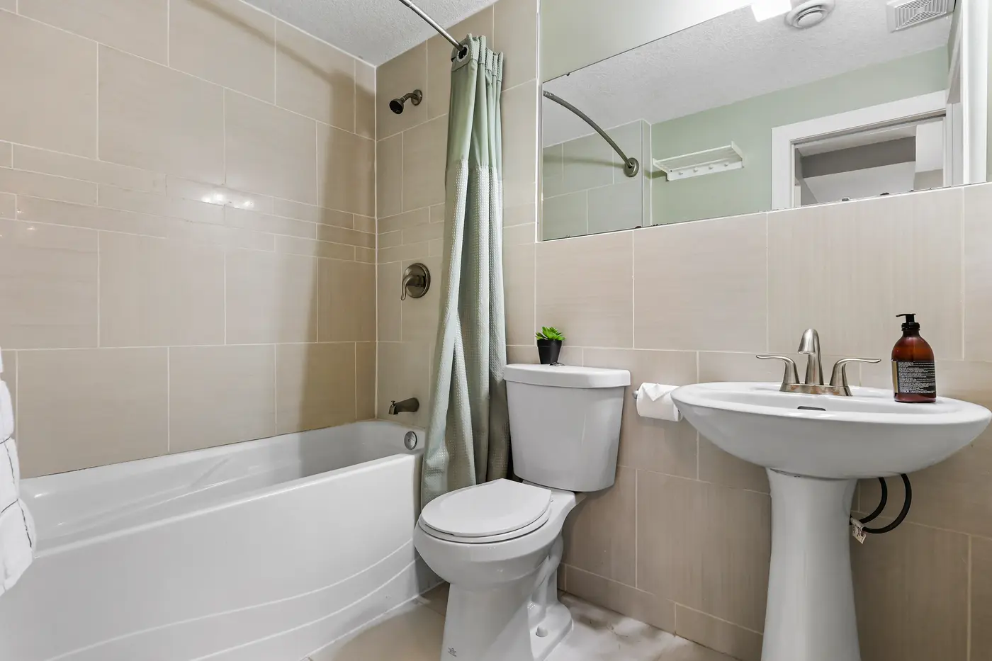 The four-piece bathroom beside the walkout bedroom — pedestal sink, tiled walls, and a full tub.