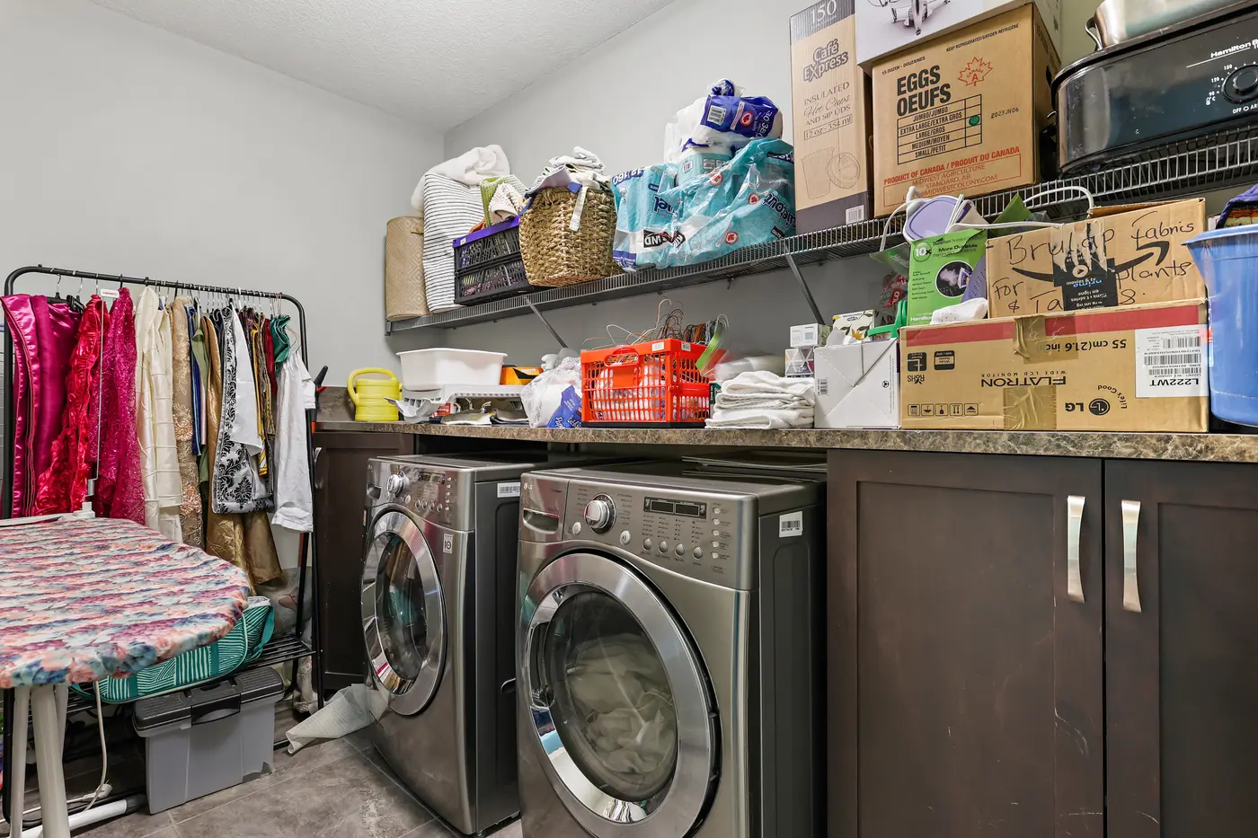 The lower-level laundry room with side-by-side front-load machines, a folding counter, and generous storage.