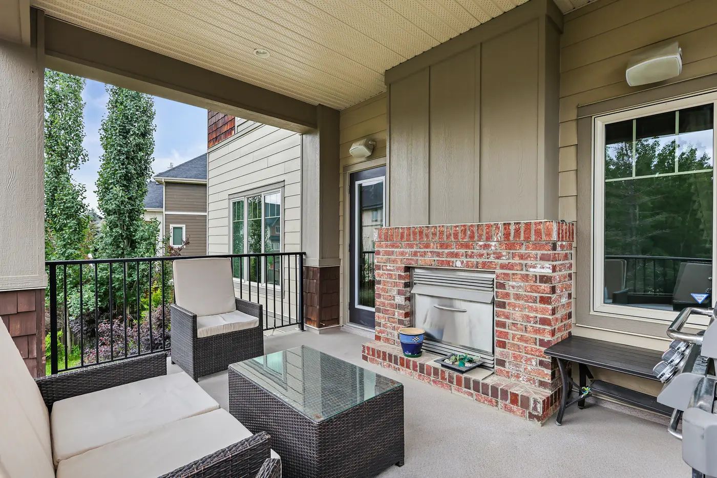 The covered patio’s built-in outdoor gas fireplace, faced in the same red brick as the house, with wicker seating pulled close.