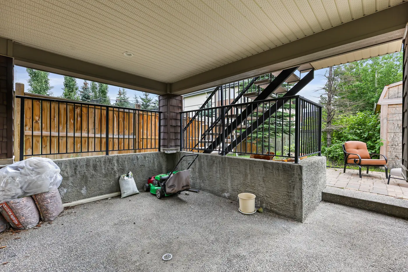 The sheltered lower patio at the walkout level, tucked under the deck beside the paver sitting area.